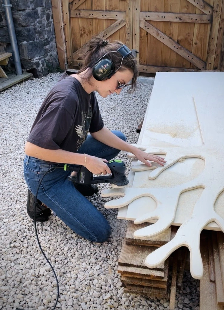 Une femme qui bricole du bois pour faire un arbre